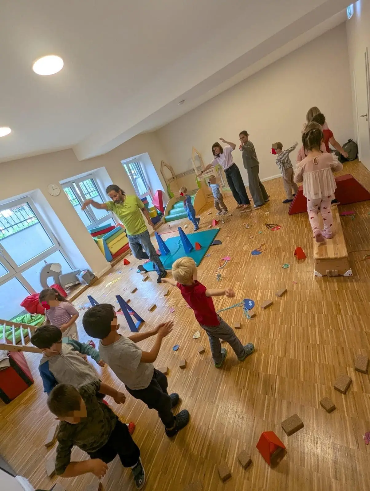 Kinder und pädagogische Fachkräfte bewegen sich im Bewegungsraum der Kita wie Meerestiere zwischen gebastelten Fischen